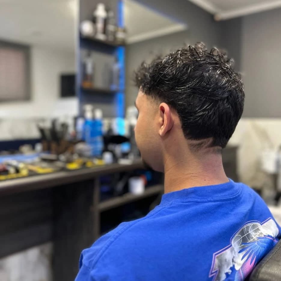 Taper fade սանրվածք՝ մաքուր անցումով և գանգուր հյուսվածքային վերևով, հետևի տեսք